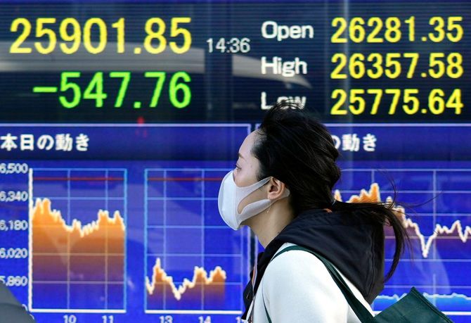 2022年2月24日、東京でマーケットボードの前を歩く人。日経平均株価は478.79ポイント(1.81%)下落し、2020年11月以来の安値となる2万5970円82銭で取引を終えた。