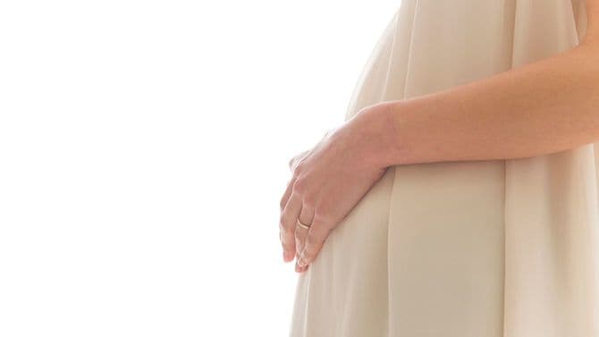妊婦さんがお腹に手を置いて