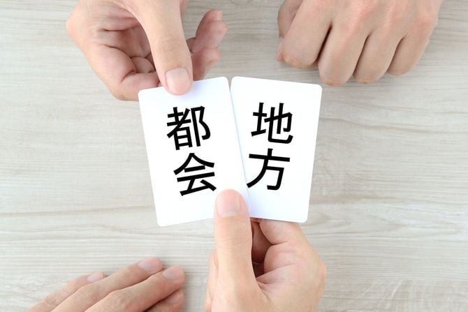 都会、地方と書かれたカードを持つ手