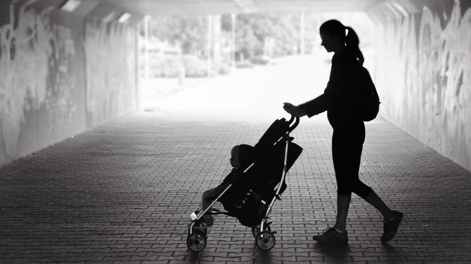 子どもの乗ったベビーカーを押して地下通路を歩く母親