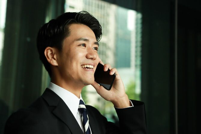 オフィスで電話を受ける、自信に満ちたスーツ姿のアジア人ビジネスマン