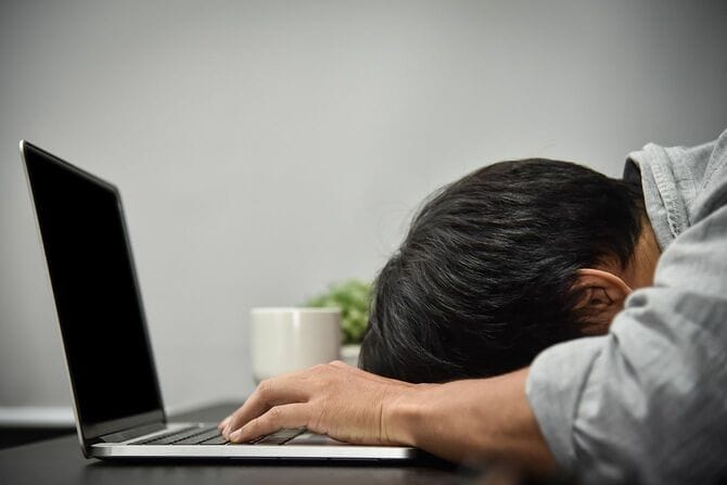 疲れた様子で机に突っ伏している人