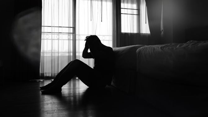 寝室で頭を抱える男性