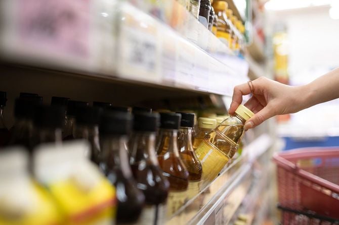 お店の棚から酢を取る女性の手