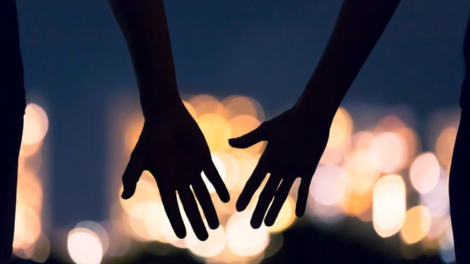 夜景を背景に向かい合う男女の手