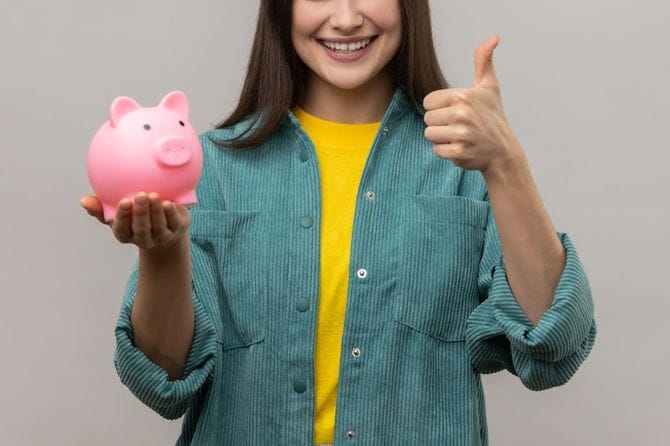 貯金箱を手に持ち親指を立てる人