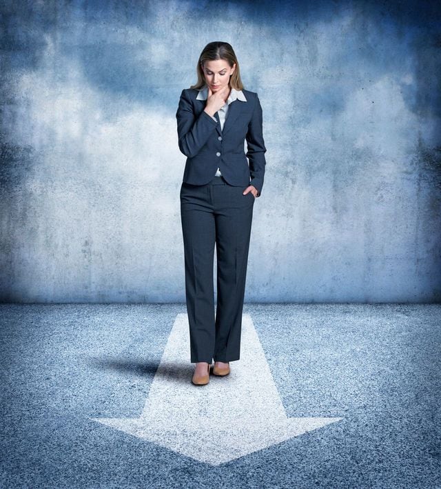 矢印の前に立ち、あごに手をやり考え込んでいる女性