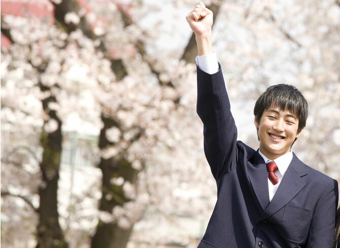 桜の木を背景にポーズをとる学生