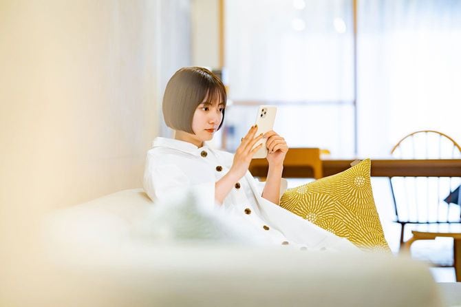 ソファに座ってスマートフォンを使用する女性