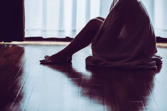 ブランケットにくるまり、床に座っている女性