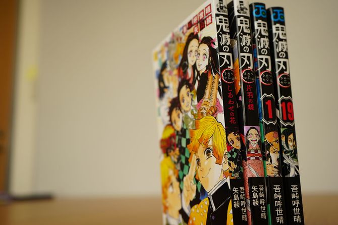 『鬼滅の刃』の小説版の背表紙(左2冊)とマンガの背表紙