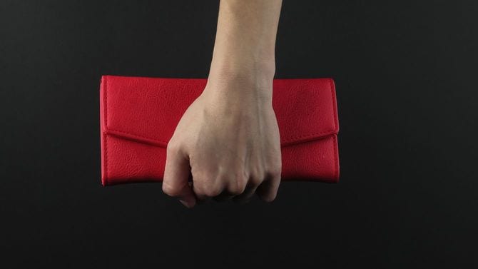女性の手が赤い革財布を持っている