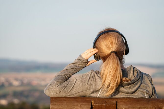 ベンチに座って音楽を聴いているヘッドフォンをした女性