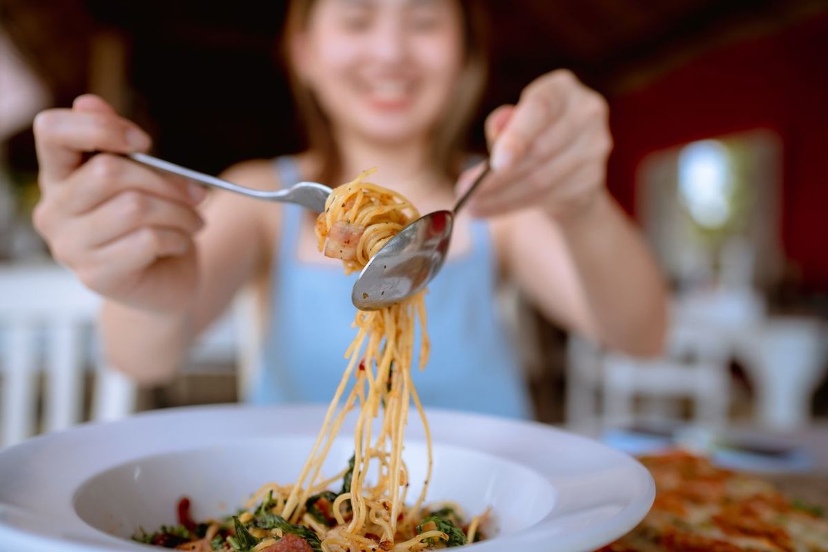 レストランでスパゲッティを食べる女性