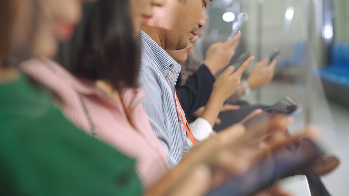 電車の中でスマホを見ている人々