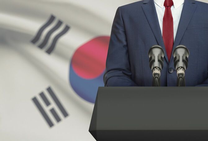 韓国国旗を背景にスピーチする政治家