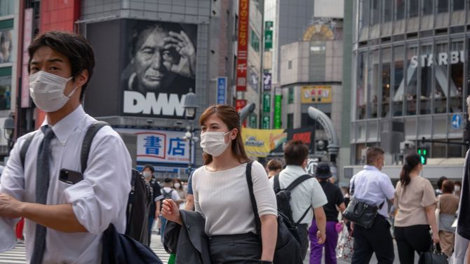 マスクを着用して渋谷スクランブル交差点を渡る人々