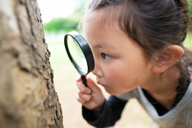 虫眼鏡で虫を探している少女