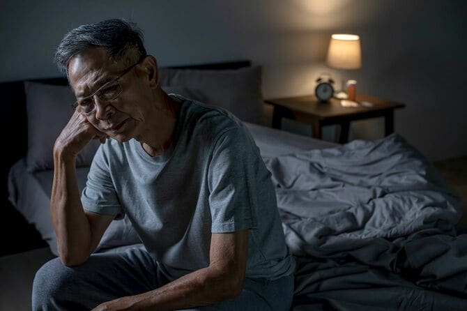 ベッドに座っているうつ病の年配の男性