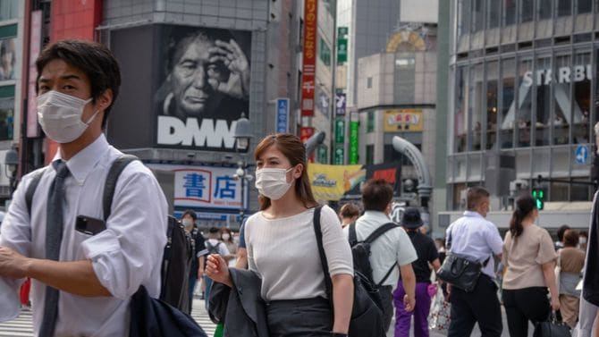 マスクを着用して渋谷スクランブル交差点を渡る人々