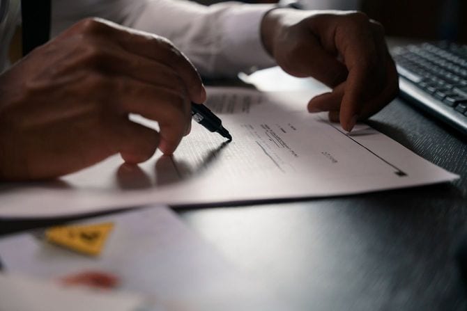 書類を注意深く読み、赤を入れている男性の手元