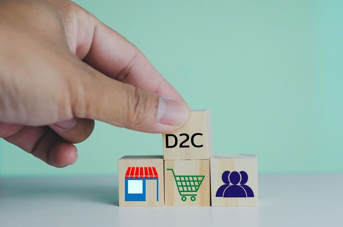 D2Cと書かれた木製ブロックを積む人の手元