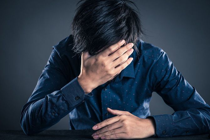 手で顔を覆う男性