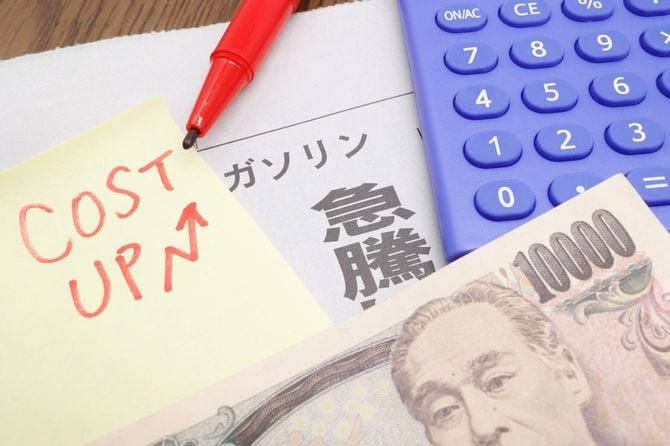 ガソリン価格急騰の見出しと電卓と一万円札