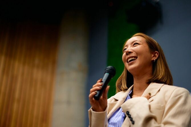 会議中にマイクに向かって話しながら笑う若い実業家