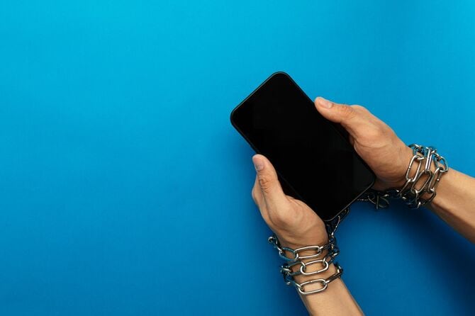 スマートフォンに鎖で繋がれた手
