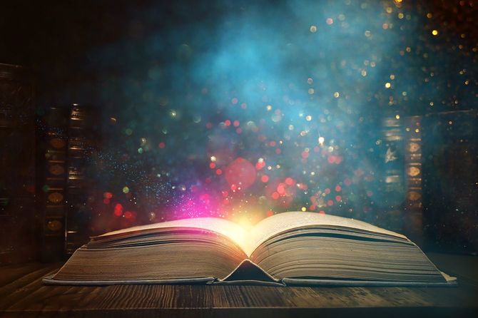 キラキラオーバーレイ付きの木製テーブルの上に開いたアンティークブックの画像