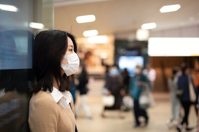 駅の壁に寄りかかっている若い女性