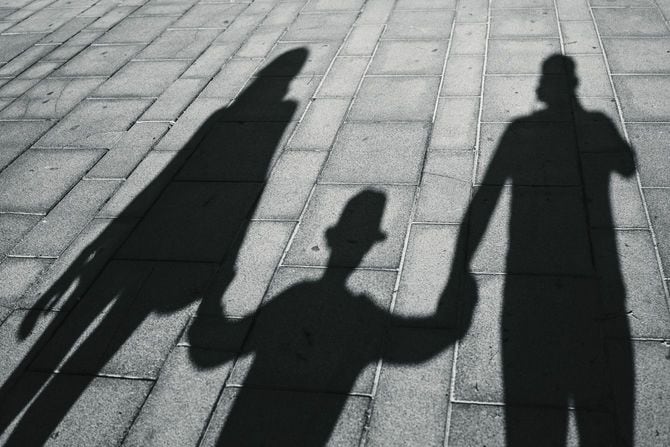 息子と手をつないで歩く両親の影
