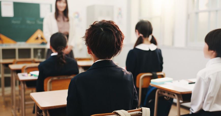 教室で着席している生徒たちに話しかけている女性の教師