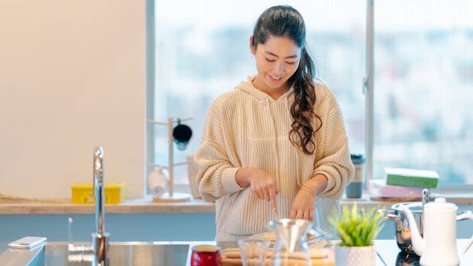 キッチンで朝食を準備する若い女性