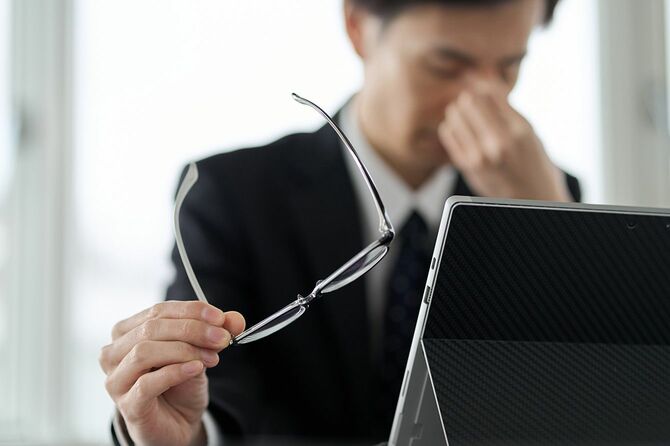 パソコン疲れで目頭を押さえる人