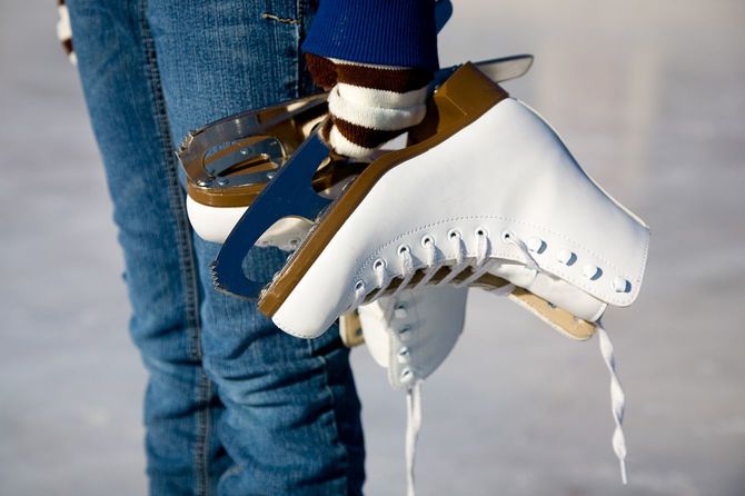 スケート靴を手に、リンクの上に立つ少女