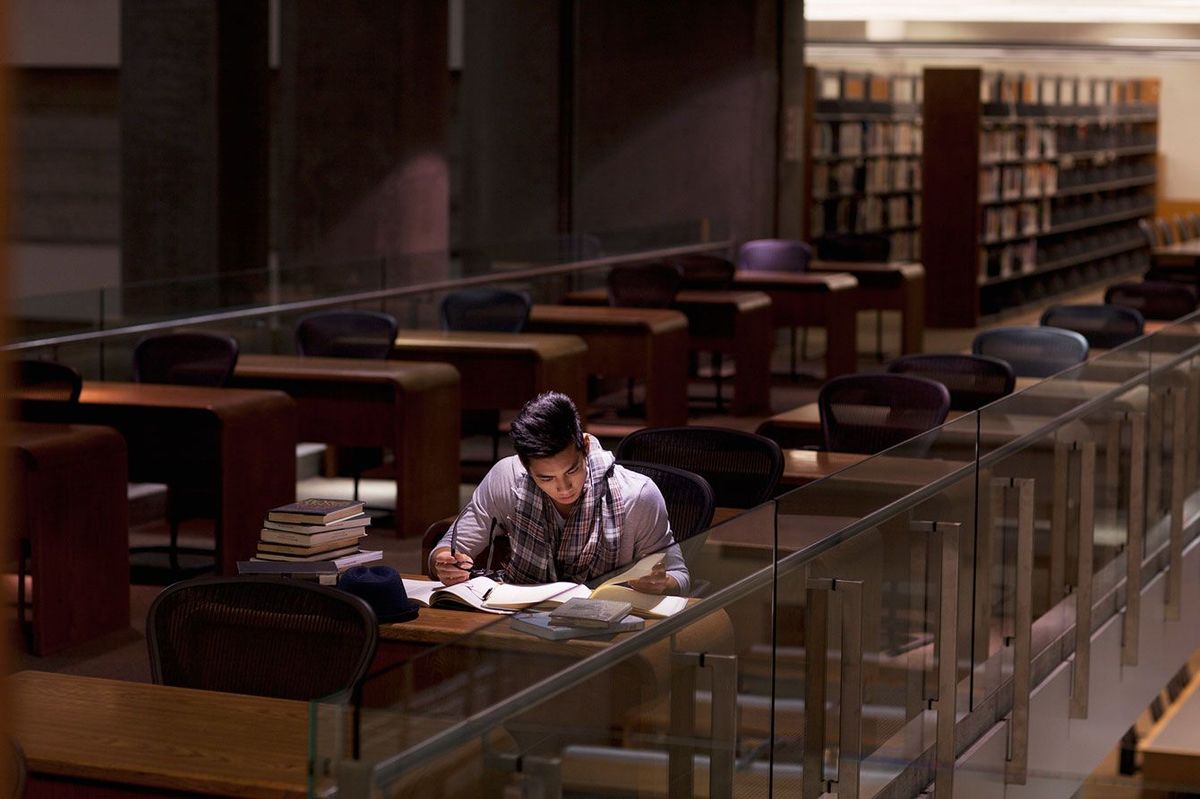 薄暗い図書館で勉強している学生