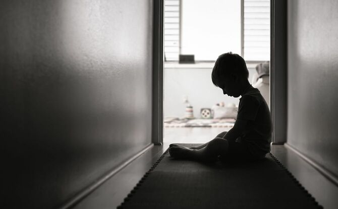 廊下で一人、悲しんで座り込んでいる少年