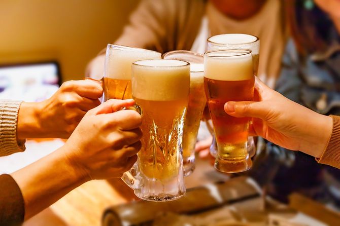 居酒屋で乾杯する多くの人々の手とマグビール