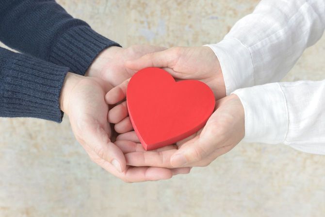 男性と女性の手で覆われたハート