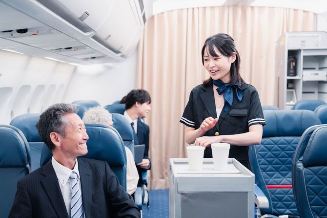 飛行機の機内で飲み物を提供する客室乗務員
