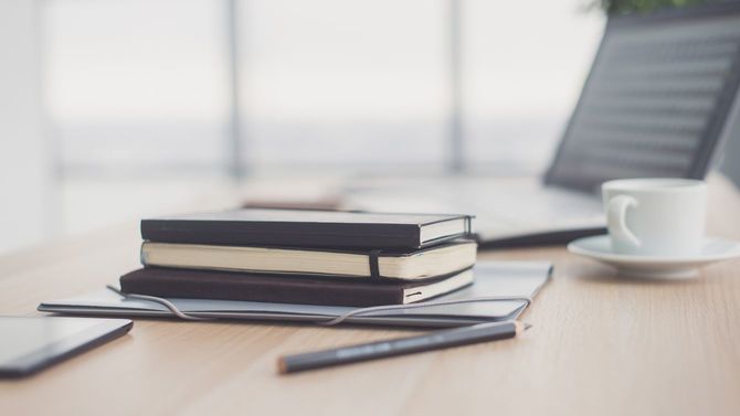 テーブルの上にペンと手帳とノートパソコン