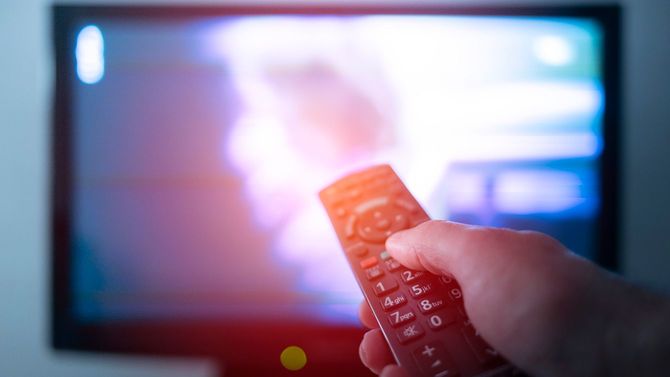 テレビの前でリモコンを持つ手元