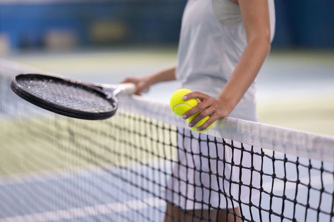 テニスコート中央のネットに手をかけているプレーヤー