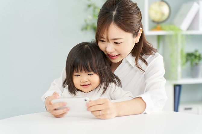 お母さんと一緒にスマートフォンを見ている女の子
