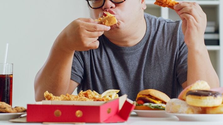 フライドチキンとハンバーガーを食べる人
