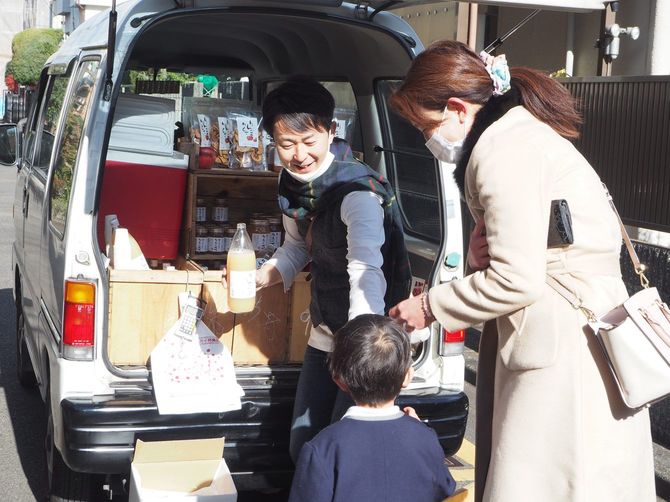 小さな子どもにリンゴジュースを差し出す笑顔の片山さん
