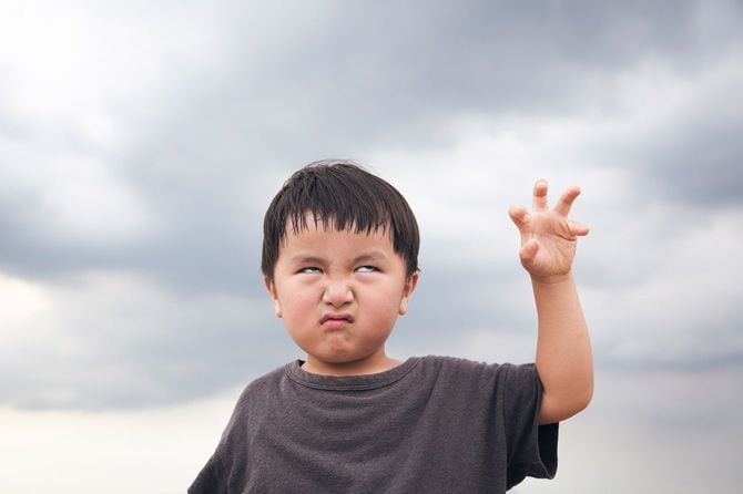 曇り空の下で怖い顔を作る少年