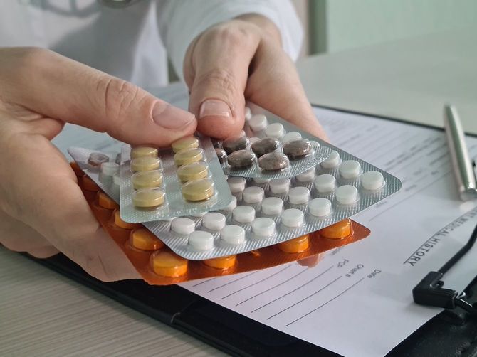 職場の接写でさまざまな錠剤のパックを持つ医師セラピスト心臓専門医